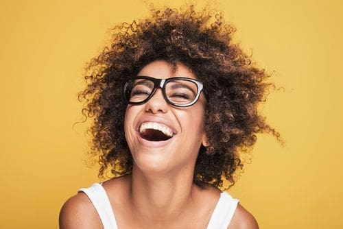 Woman laughing against a yellow background