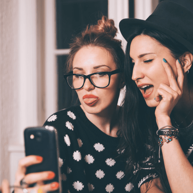 Two young women taking a selfie with one of them sticking out her tongue