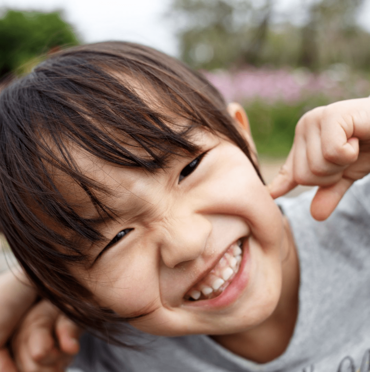 Young child grinning and pointing to their teeth