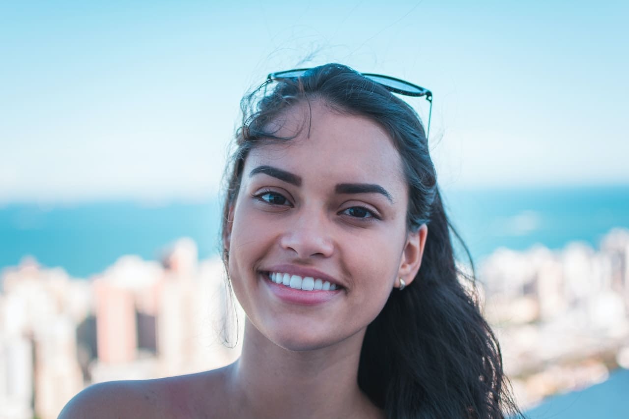 Young woman with sunglasses grinning outdoors