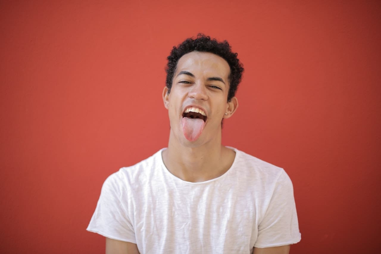 Person sticking out their tongue against a red background