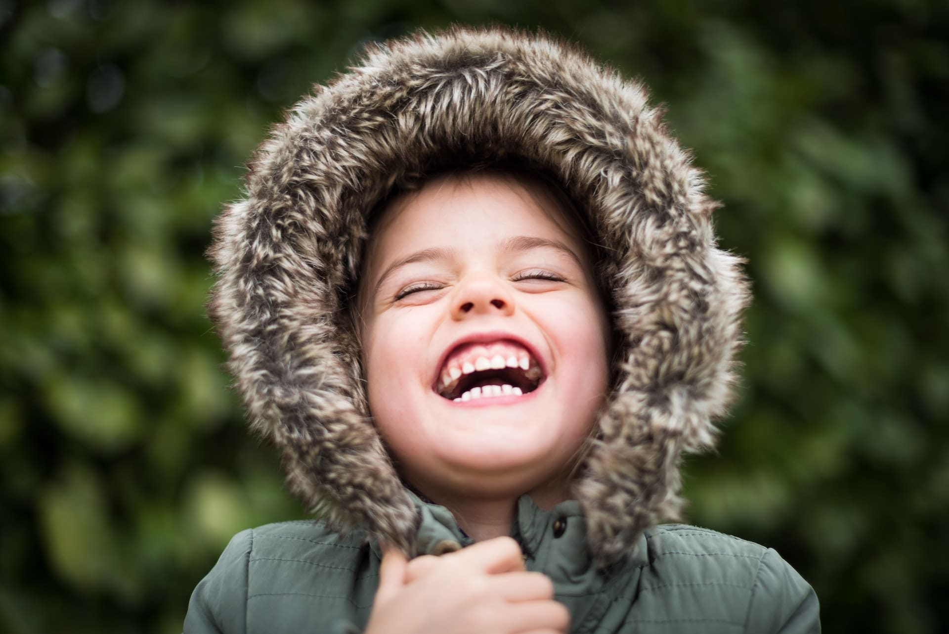 Baby laughing while wearing a coat with a fuzzy hood