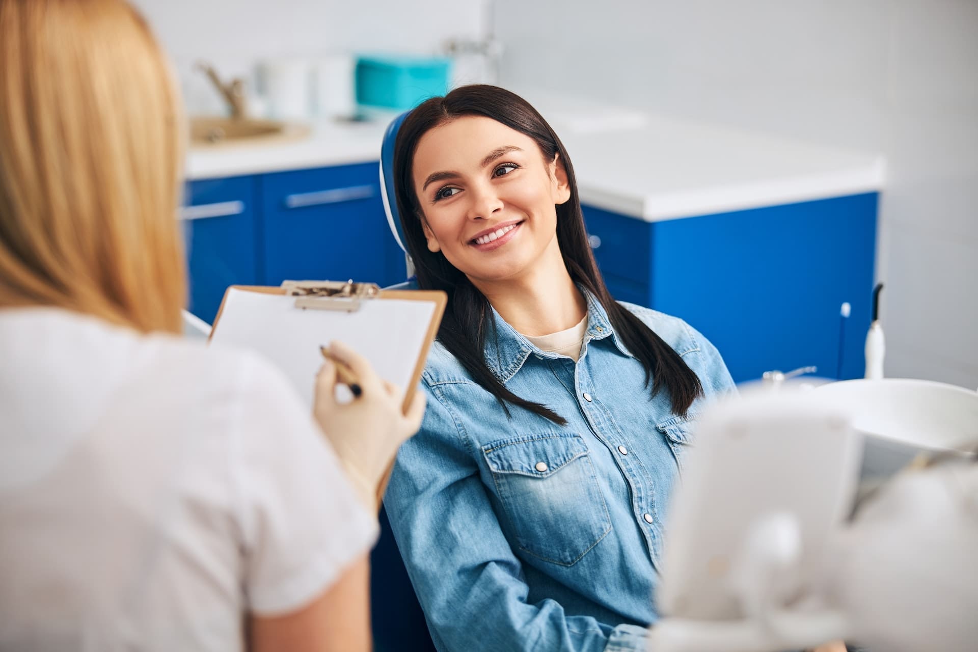 Young woman sitting in dental chair and smiling at her cosmetic dentist in Lexington