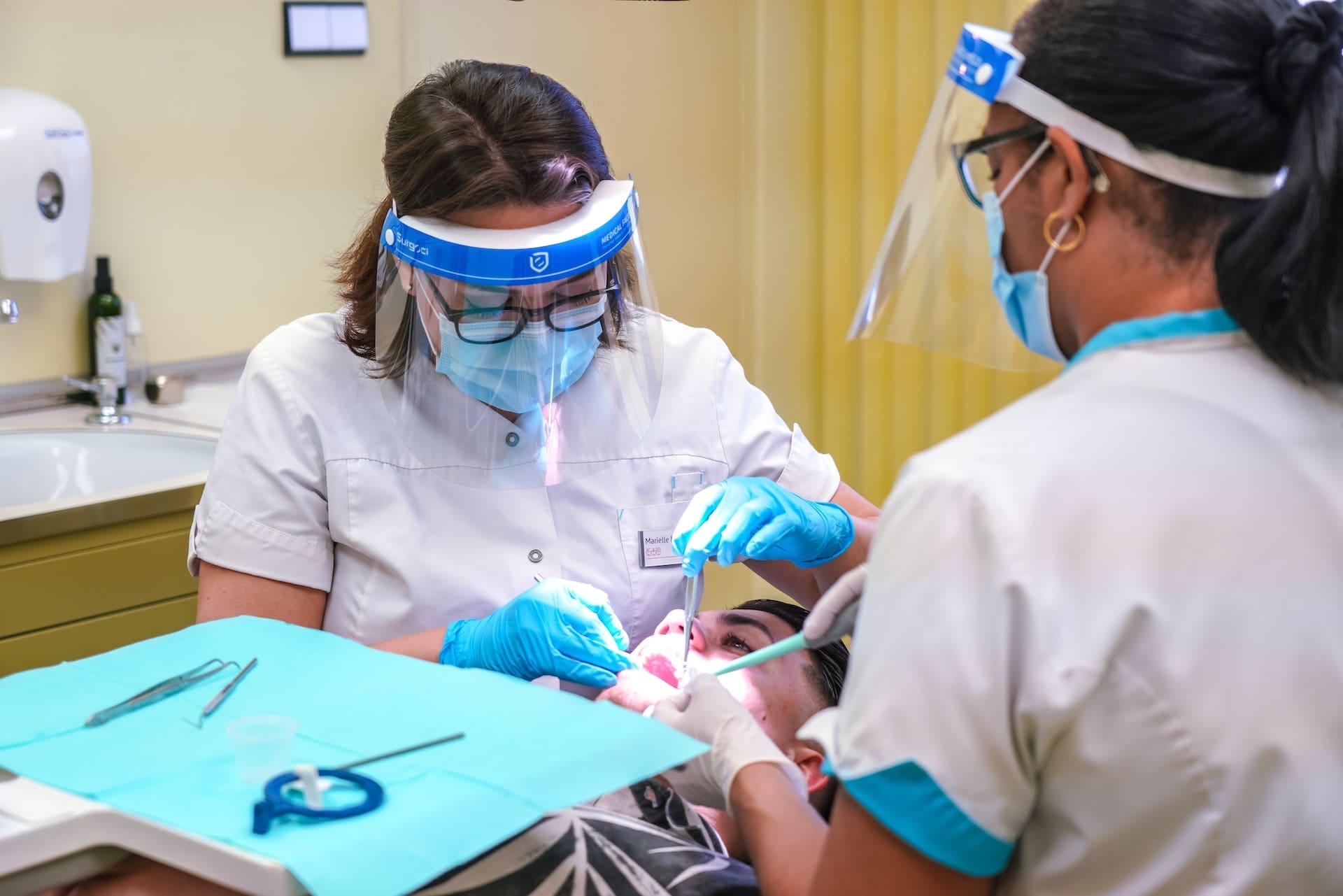 Dentist and assistant performing tongue tie treatment on an adult woman