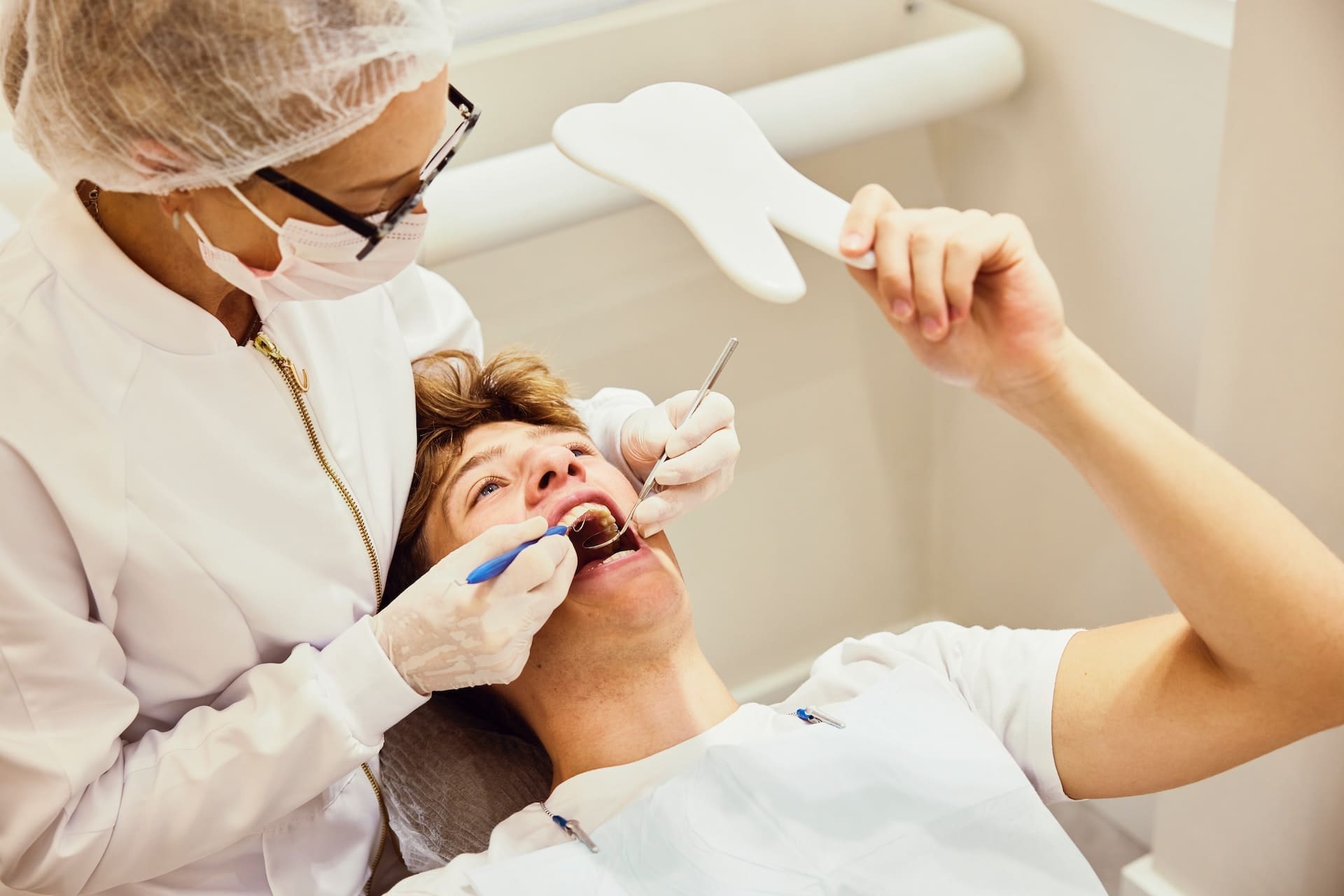 Dental patient looking at his mouth in a mirror while receiving dental treatment