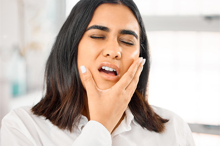 Woman experiencing dental pain due to untreated lip or tongue tie