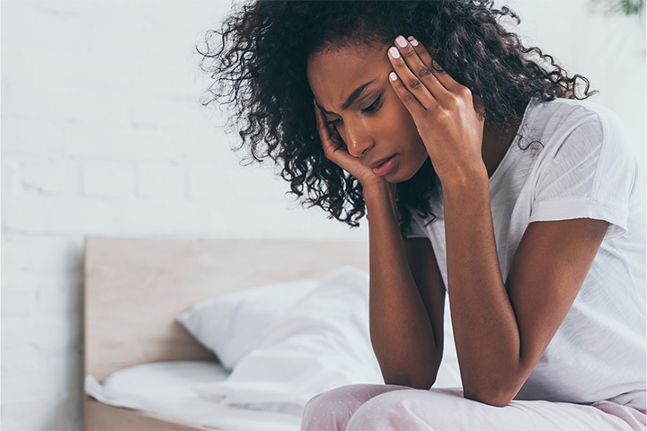 Tired, sad woman sitting on her bed