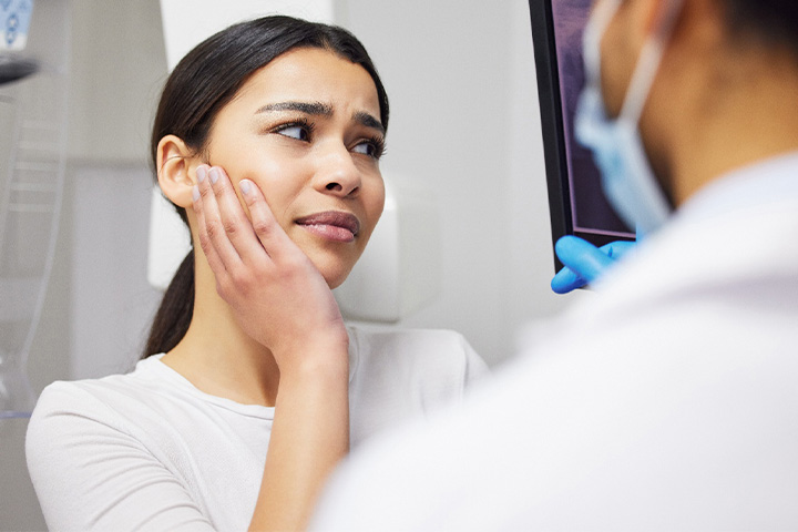 Young woman holding cheek and looking at X-rays