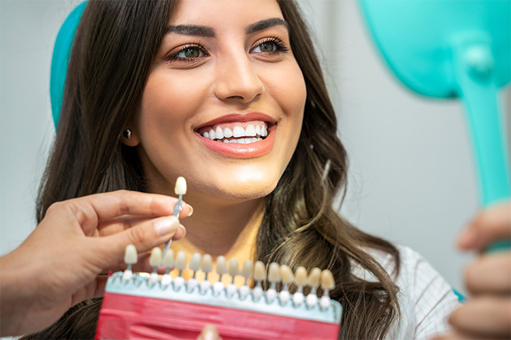 A dentist comparing a woman’s smile to a shade guide