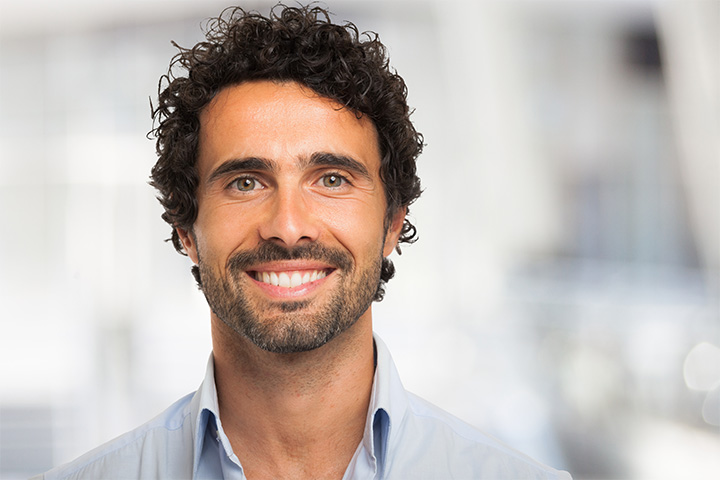 A portrait of a smiling, curly-haired man