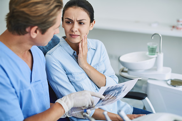 Patient in Lexington holding cheek and talking to dentist