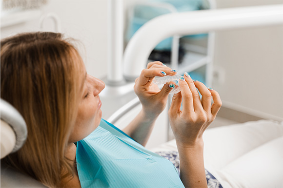 Patient holding clear aligner in treatment chair