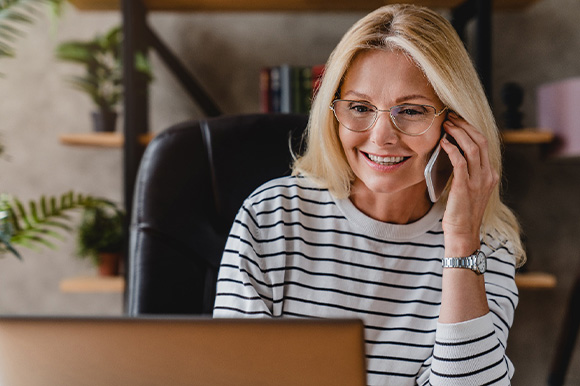 Woman with glasses smiling while talking on phone