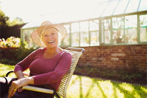 Older woman sitting outside and happy with her new smile.