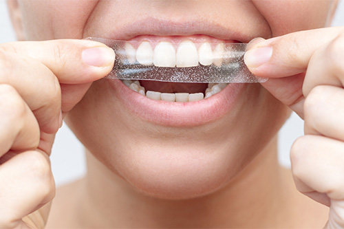 Person with whitening strip in their hands.
