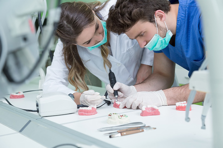 A dental technician further refining a denture.