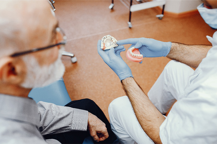 A dentist showing dentures to an older man.