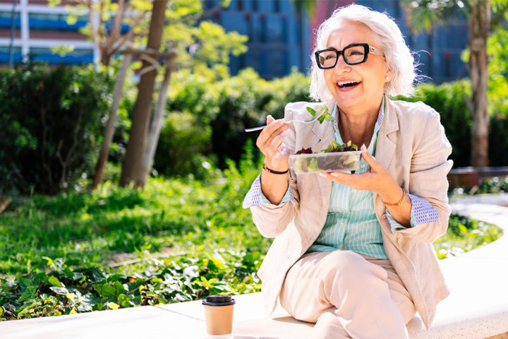 Lady smiles while eating salad.