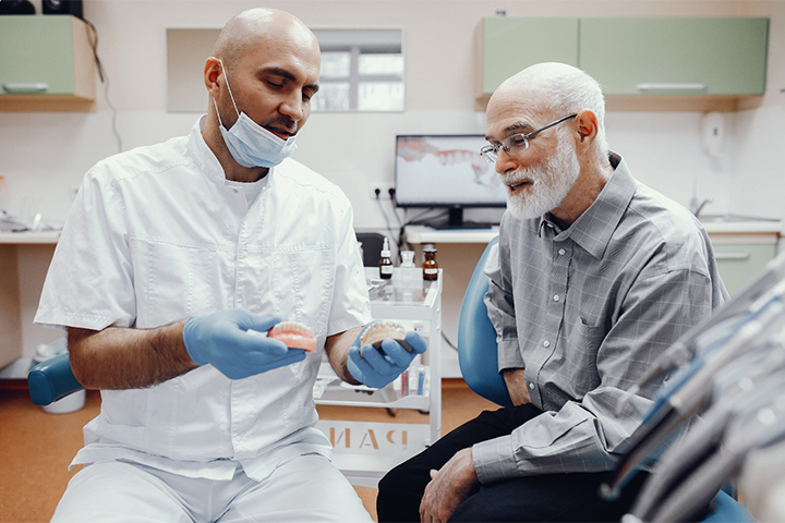 A dentist explaining to his patient how dentures work.
